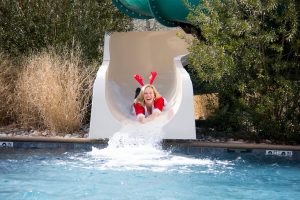 Woman in santa outfit sliding down water slide